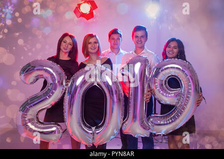 New Year party concept. Group of young friends holding silver colored numbers 2019 and throwing confetti Stock Photo