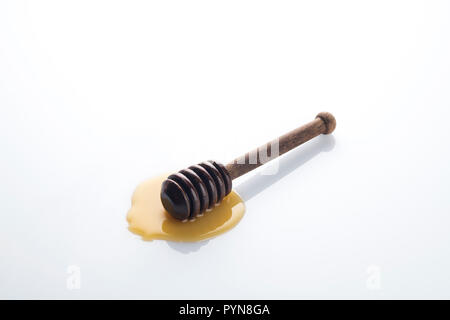 Brown Wooden Honey Dipper with Golden Yellow Honey on White Background Stock Photo