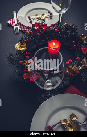 Beautiful Christmas dinner place setting for two. Table decorated with a wreath and a candle. Stock Photo