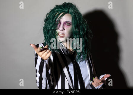 A young woman dresses up for Halloween in a pinstripe suit and green hair. Stock Photo