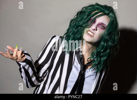 A young woman dresses up for Halloween in a pinstripe suit and green hair. Stock Photo