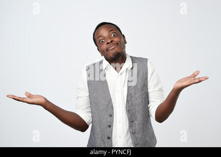 doubtful african man shrugs shoulders with confusion Stock Photo