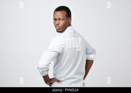 Man in white shirt looking behind at camera over his shoulder showing critical attitude. Stock Photo