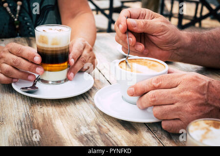 Close-up of old aged hands with coffee cups in a cafe with wood trendy chic table. colors and morning breakfast drink concept for mature people couple Stock Photo