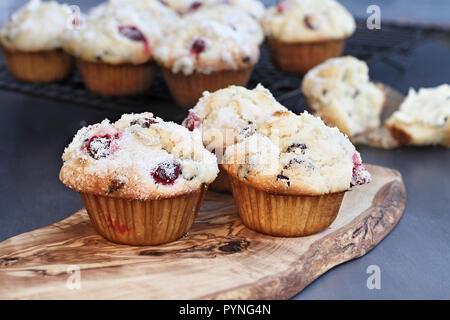 Cranberry Muffins with lemon sugar topping on a rustic cutting board with loose berries. Extreme shallow depth of field with selective focus on muffin Stock Photo