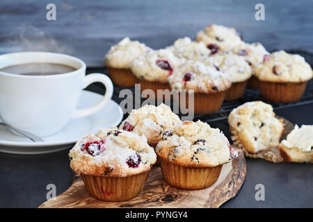 Cranberry Muffins on a wood cutting board with more cooling on a bakers rack. Extreme shallow depth of field with selective focus on center muffin. St Stock Photo