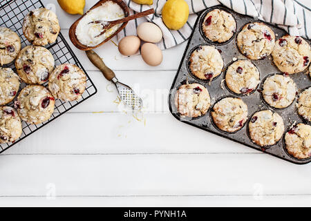 Cranberry Muffins in a muffin tin with fresh eggs, sugar, lemons and lemon zest over a rustic white table  background. Image shot from above with free Stock Photo