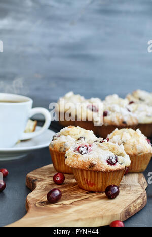 Cranberry Muffins on a wood cutting board with more cooling on a bakers rack. Extreme shallow depth of field with selective focus on muffin in foregro Stock Photo