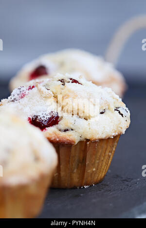 Cranberry Muffins with lemon sugar topping on a rustic slate serving tray. Extreme shallow depth of field with selective focus on muffin in center. Stock Photo