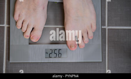 Male feet on glass scales, men's diet, body weight, close up, man standing on scales, top down view, athlete foot Stock Photo