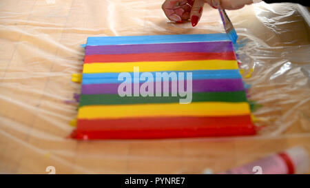 Female artist painting a rainbow with acrylic colors on canvas, hoe made art, DIY tutorial, colorful Stock Photo