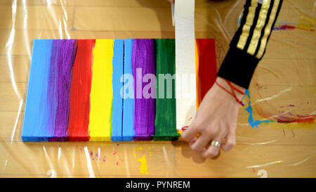 Female artist painting a rainbow with acrylic colors on canvas, hoe made art, DIY tutorial, colorful Stock Photo