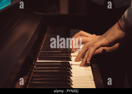 women's hands on the piano keys, playing a melody. Stock Photo