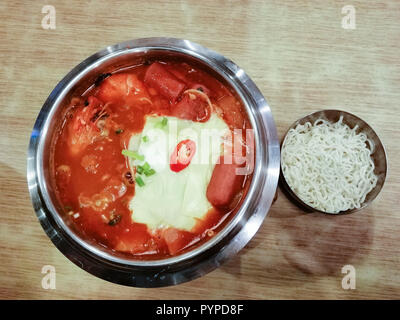 Delicious Korean food Yukgaejang spicy seafood soup with cheese, Yukgaejang Hot pot is Korean stew made with kimchi, noodles, cheese, ham, sausage, mu Stock Photo