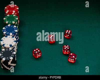 Poker chips of different colors and several dice on a green mat Stock Photo