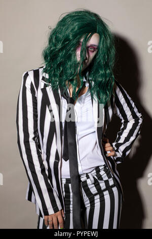 A young woman dresses up for Halloween in a pinstripe suit and green hair. Stock Photo