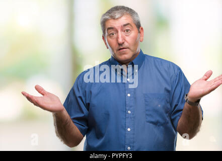 Handsome senior man over isolated background clueless and confused expression with arms and hands raised. Doubt concept. Stock Photo