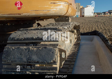 Rear view and closeup of tracks on yellow excavator at construction site Stock Photo