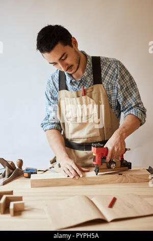 Carpenter drills a hole with an electrical drill Stock Photo