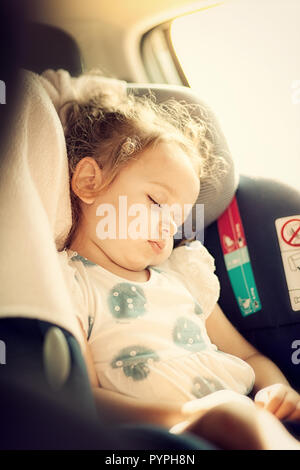 Cute blond baby sleeping in baby car seat. Safety Concept. Stock Photo