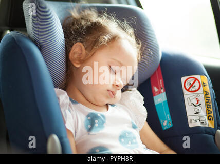 Cute blond baby sleeping in baby car seat. Safety Concept. Stock Photo