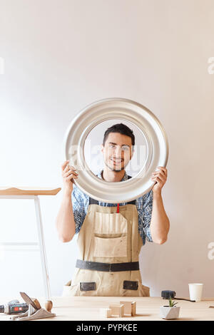 Confident young woodworker standing next to workbench in his carpentry workshop Stock Photo