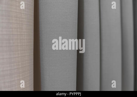 Close-up view of bright curtain in thin and thick vertical folds made of dense fabric.Textured abstract backgrounds and wallpapers.Materials and textiles. Stock Photo