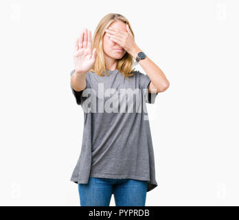 Beautiful young woman wearing oversize casual t-shirt over isolated background covering eyes with hands and doing stop gesture with sad and fear expre Stock Photo