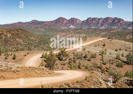 An isolated outback dirt road winds its way through the desert valley towards the distant, Central Flinders Range. Stock Photo