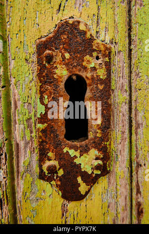 Old rusty keyhole in wooden door with peeling paint on Calle Marques De Cubas in the village of Jacarilla, Spain Stock Photo