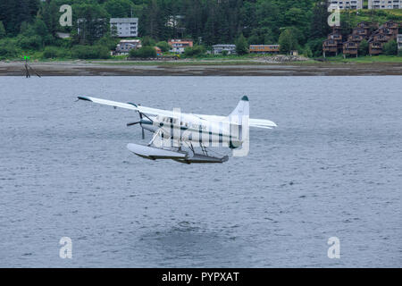 A Small Sea Plane Taking Off over blue water in Alaska Stock Photo