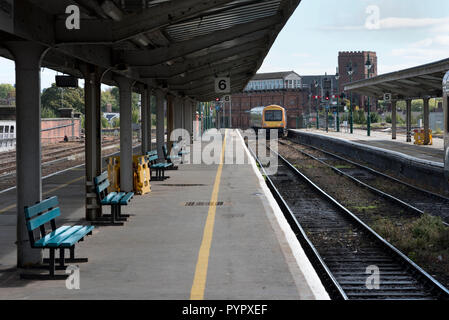 A passenger train departs from Shrewsbury railway station, Shropshire, UK. Shrewsbury Abbey can be seen in the background, Stock Photo