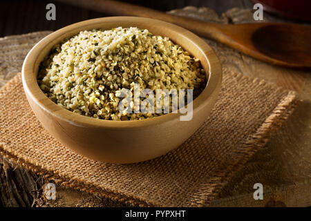 Heap of raw, organic hemp seeds in wooden bowl on burlap on rustic table background Stock Photo