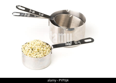 Heap of raw, organic hemp seeds in metal measurement scoop over white background Stock Photo