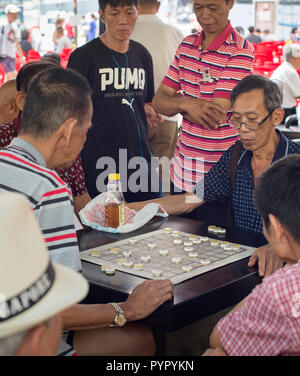 SINGAPORE - FEB 17, 2017: Men play checkers on a street of Chinatown district in Singapore. Ethnic Chinese began settling in Chinatown circa 1820 Stock Photo