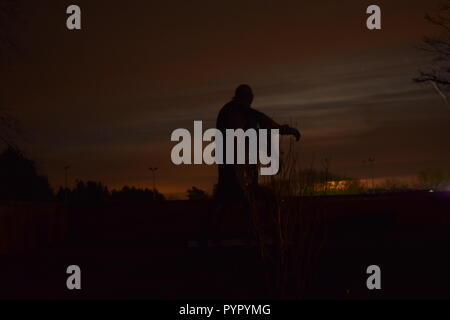 Timeline of the rising moon during the night  dusk sky viewed from a Bronze sculpture silhouette in the military cemetery Reimsbach an der Saar Germany Stock Photo