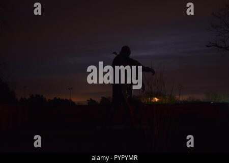 Timeline of the rising moon during the night  dusk sky viewed from a Bronze sculpture silhouette in the military cemetery Reimsbach an der Saar Germany Stock Photo