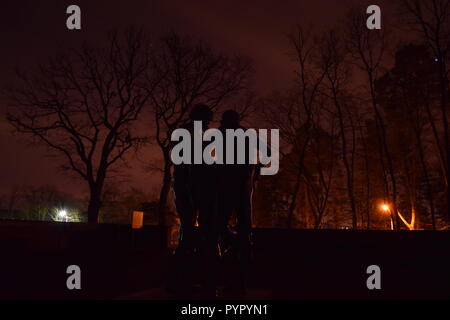 Timeline of the rising moon during the night  dusk sky viewed from a Bronze sculpture silhouette in the military cemetery Reimsbach an der Saar Germany Stock Photo