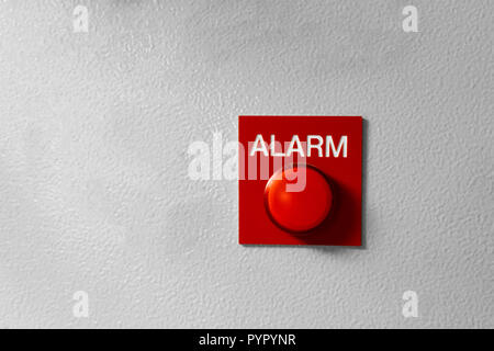 Red Alarm button signal on the painted grey wall. Concept of any alarm situation - fire, bankrupt, robbery etc. Stock Photo