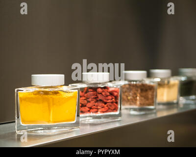 modern cuisine: glasses of curry, goji berries and different spices and herbs standing on a kitchen shelf Stock Photo