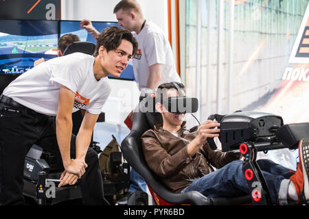 MOSCOW, RUSSIA - OCTOBER 27 2018. Happy and excited man playing racing video game with virtual reality headset Stock Photo