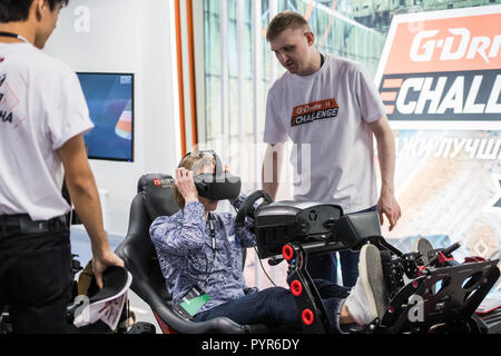 MOSCOW, RUSSIA - OCTOBER 27 2018. A woman is playing a driving game with virtual reality gear on. Stock Photo