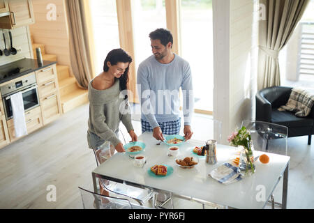 Happy couple setting table for breakfast Stock Photo