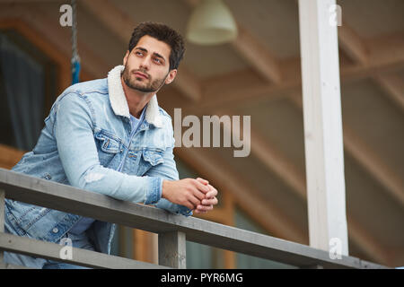 Dreamy young man resting on balcony Stock Photo
