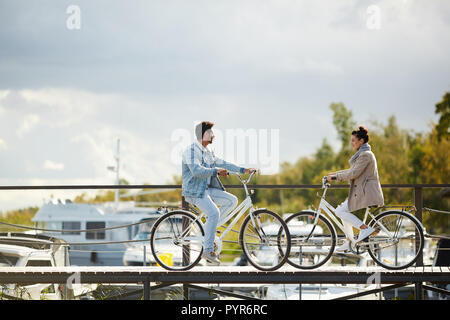 Beautiful couple on bicycles meeting on pier Stock Photo