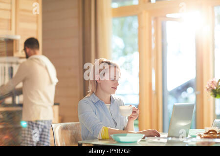 Woman Using Laptop At Kitchen Stock Photo