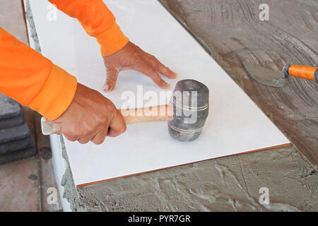 Construction worker tiler is tiling, Tiler installing ceramic tiles on a floor Stock Photo