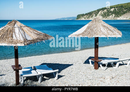 Beach umbrellas and sun beds on the ocean. Vacation and travel to different countries Stock Photo
