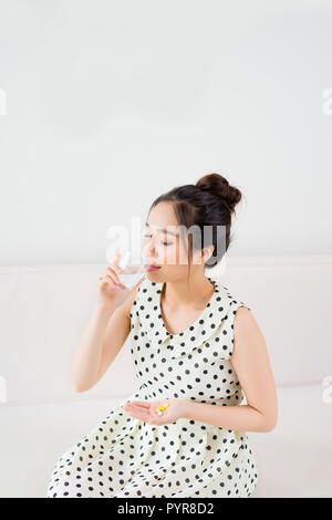 Upset Vietnamese woman on couch at home in the living room Stock Photo