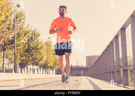 Young fitness sport man running in sunset for Marathon in a urban area in Fitness training outdoors Work out Sports living Active Healthy lifestyle. Stock Photo